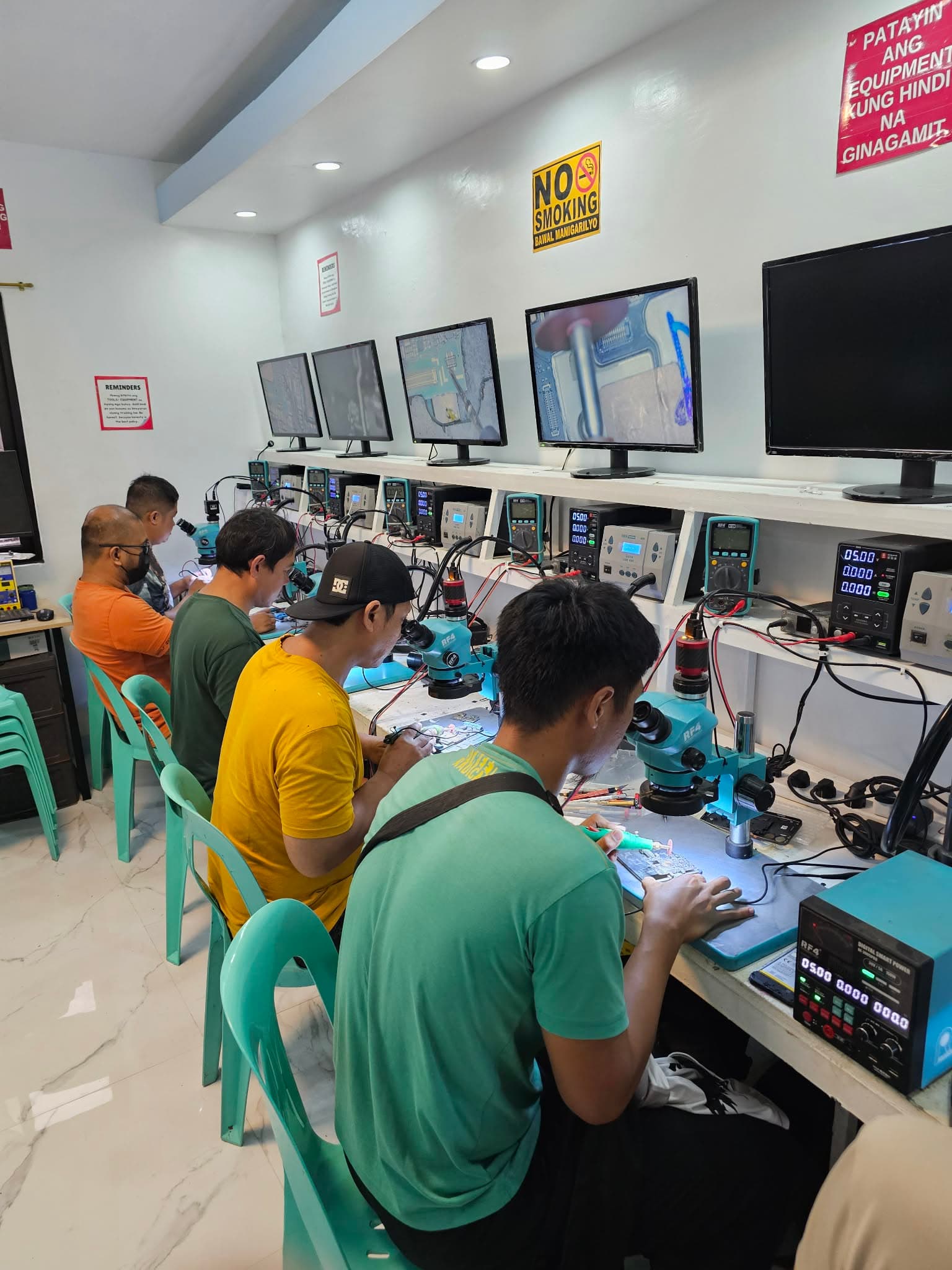 Trainees working at microscope repair benches in the HardTech lab.