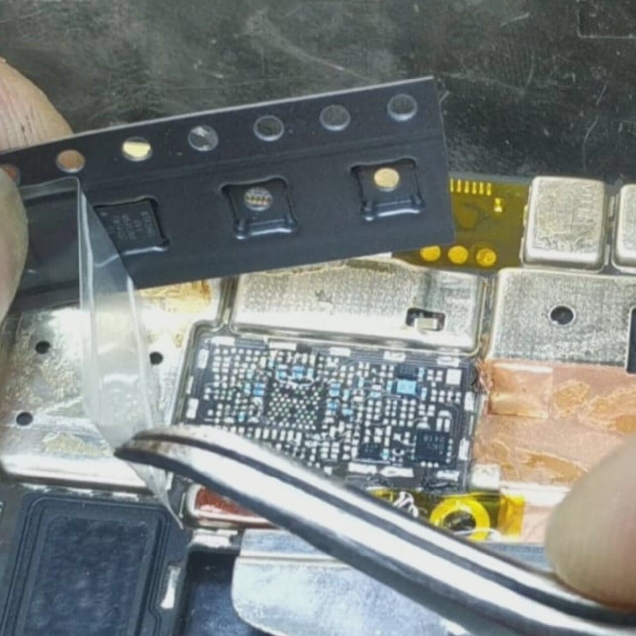 Close-up of electronic components and a circuit board during repair work.