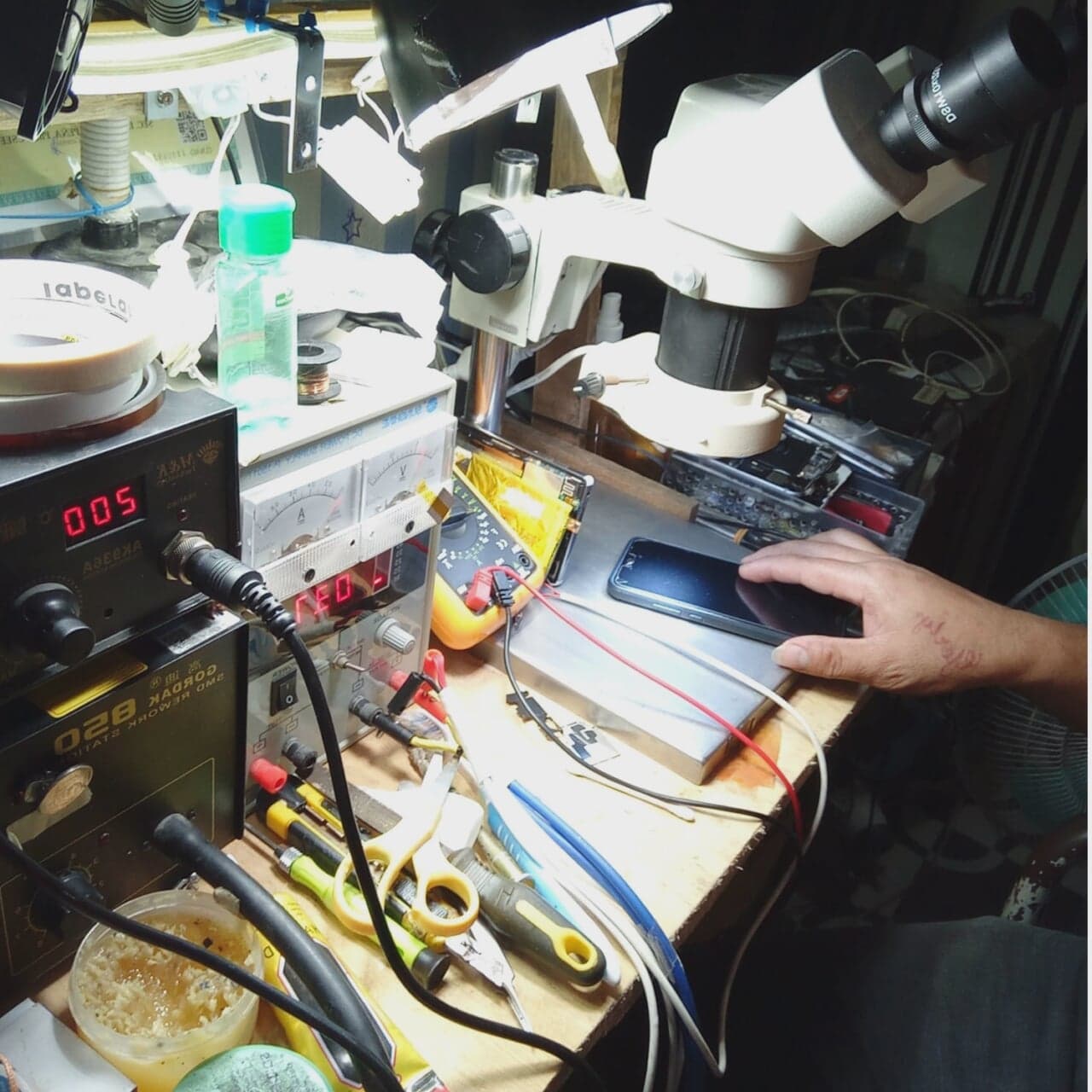 Microscope repair workstation with test equipment and a device on the bench.