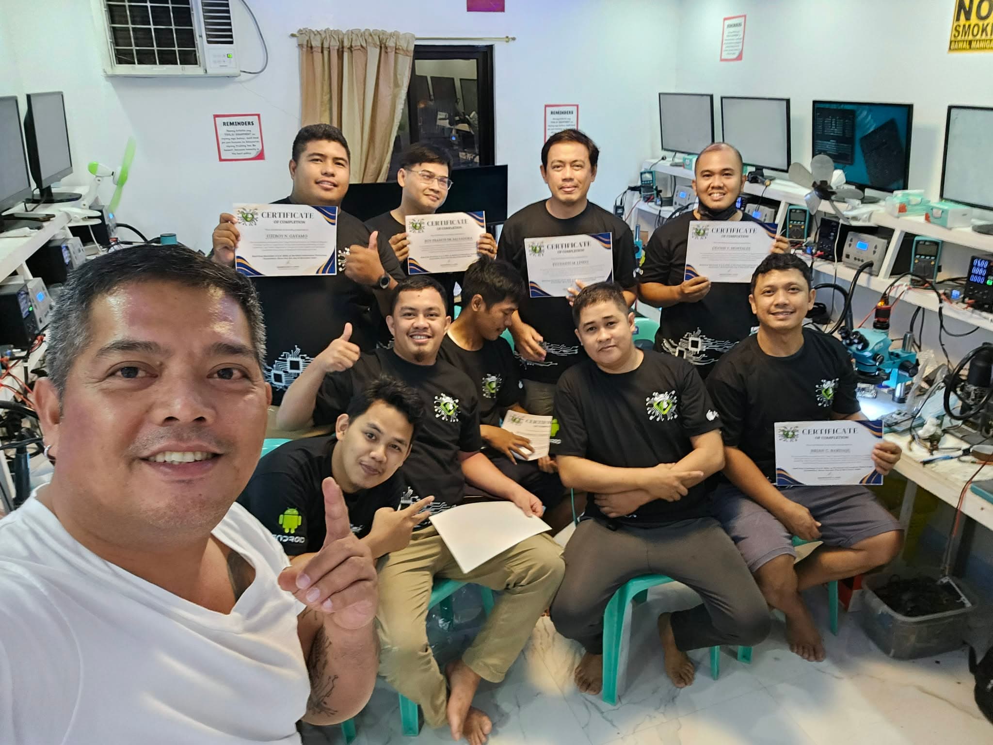 Group photo of trainees holding completion certificates in the training lab.