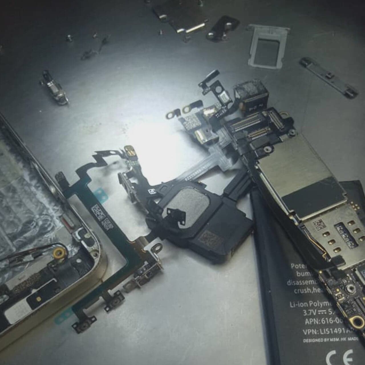 Disassembled mobile-device components arranged on a repair table.