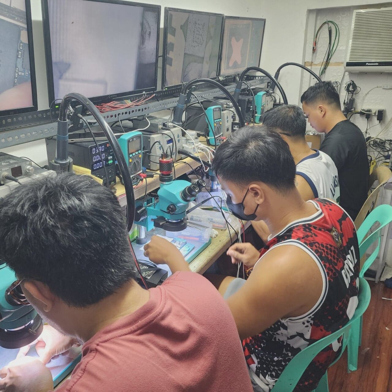 Trainees seated at microscope stations during hands-on board work.