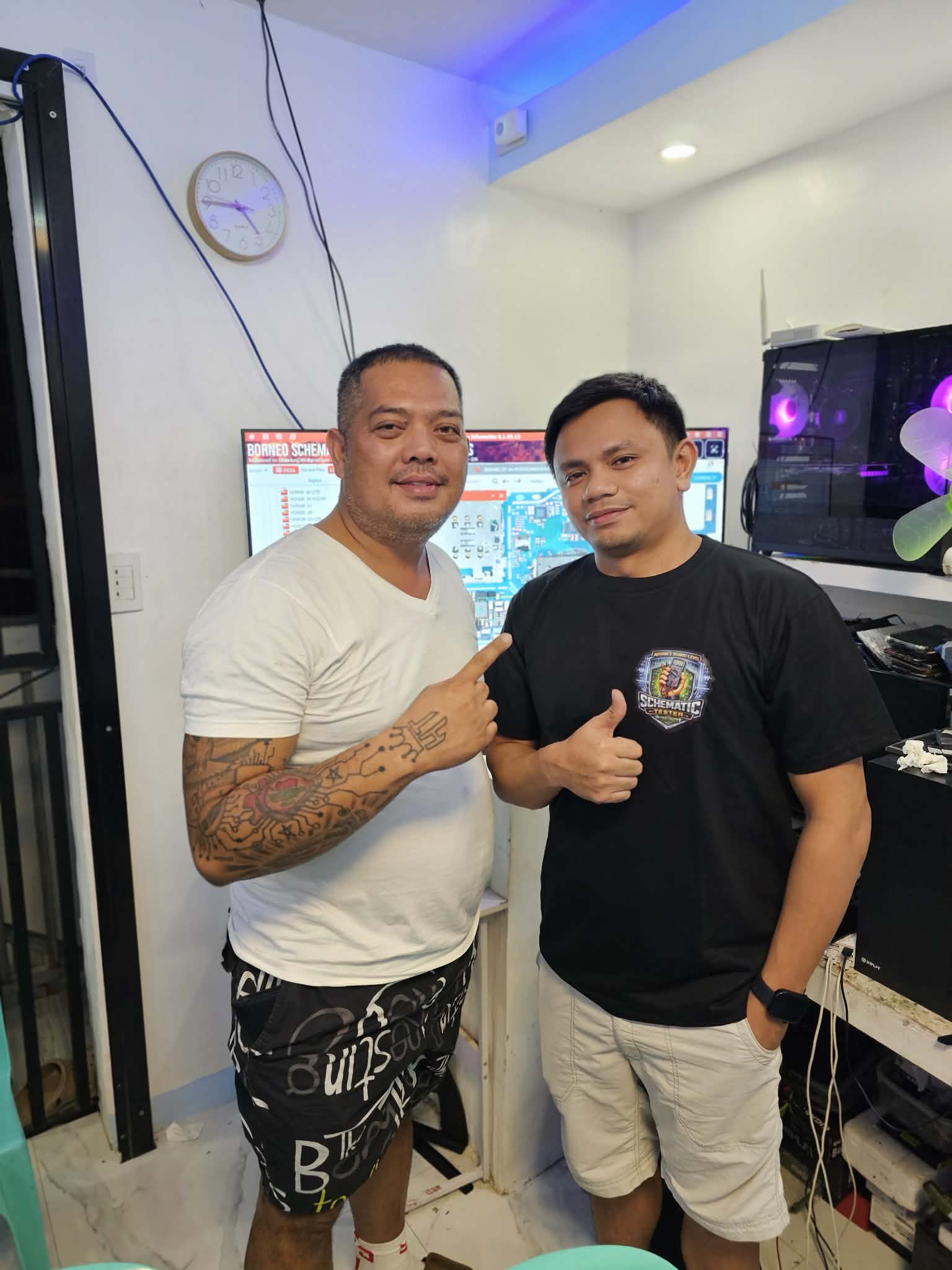 Two people posing beside a monitor and repair equipment.